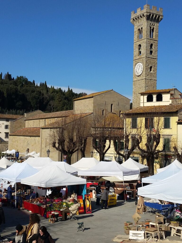 Market day on the main square of Fiesole with the cathedral and bell tower overlooking the historic hill town above Florence.